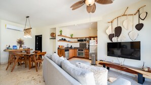 A modern living room with a grey sofa, wooden dining table, and chairs. A kitchen with a microwave, oven, and sink is visible in the background. - Ocean Elegance
Contemporary Beachfront Escape at El Faro Resort Living (Playa del Carmen)