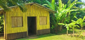 A small, single-story building with a bamboo exterior, a central door, and a small porch area.