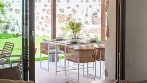 An outdoor dining area with a stone wall backdrop, wicker chairs, and a table set for two. - RURAL HOUSE CERCADO DE DON PACO (Santa Lucia De Tirajana (Capital Municipal))