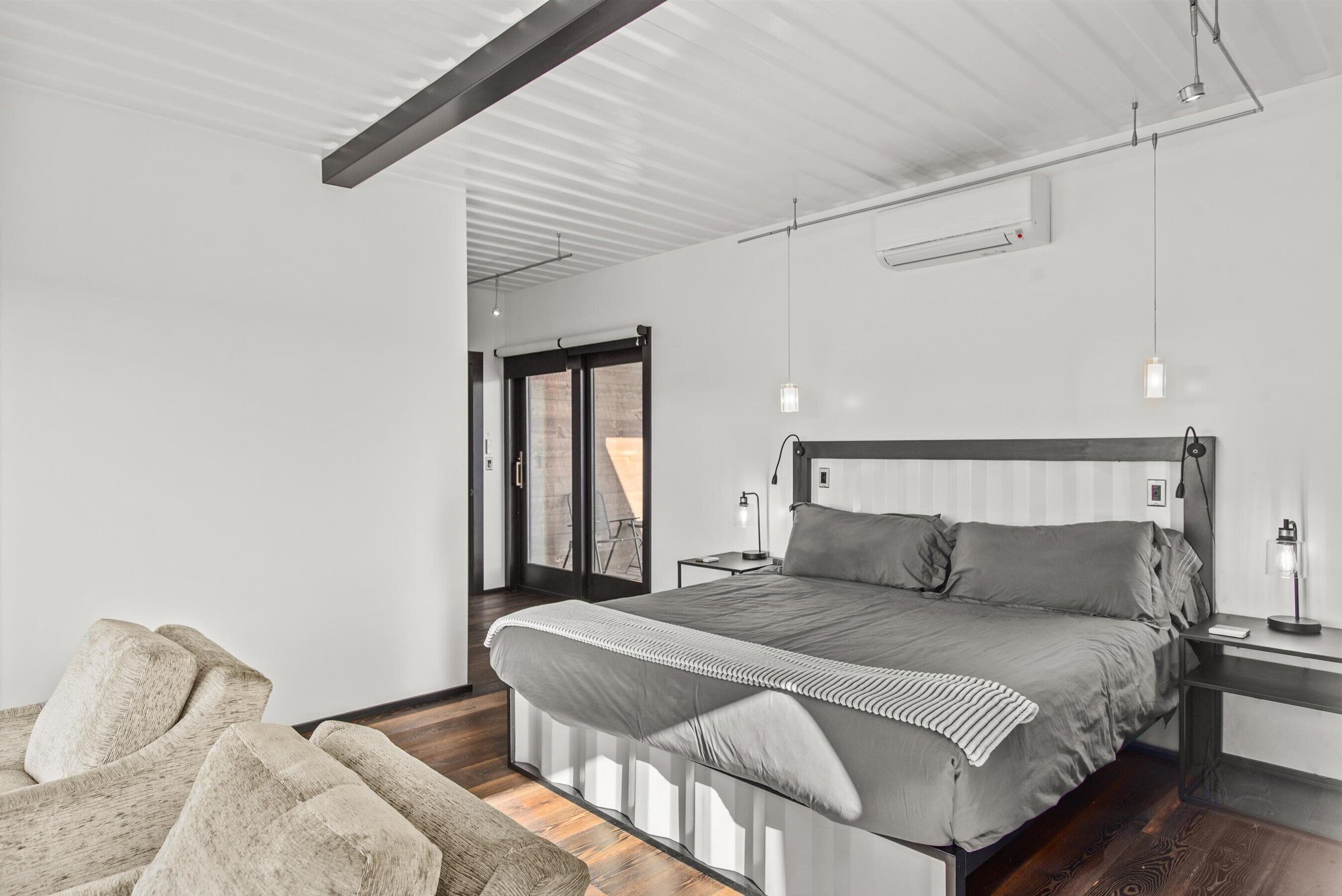 A modern bedroom with a large bed, bedside tables, and a view through a glass door.