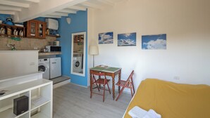 A compact living space with a kitchen, washing machine, and a dining area with chairs. - Via Laura - cozy studio (Florence)