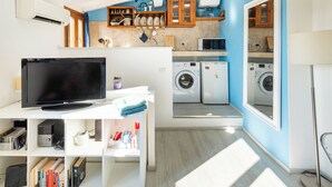 A compact living space with a flat-screen TV, a washing machine, and a microwave. - Via Laura - cozy studio (Florence)