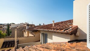 A rooftop with terracotta tiles, a chimney, and a white wall with a window. - Via Laura - cozy studio (Florence)