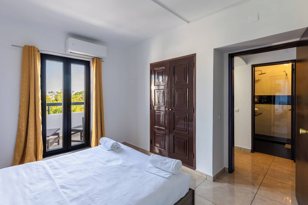 A hotel room with a bed, a sliding door to the balcony, and a separate bathroom.