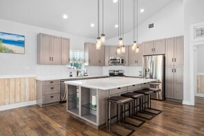 Una cucina moderna con una grande isola, elettrodomestici in acciaio inossidabile e illuminazione a sospensione.