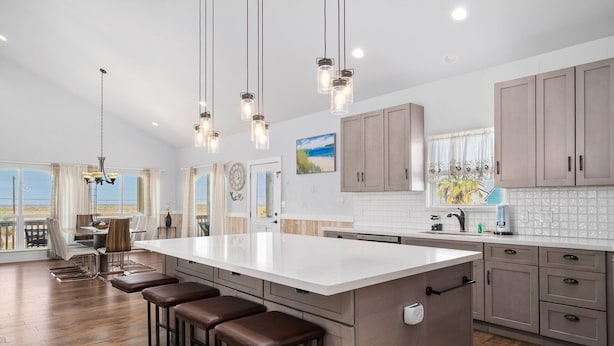 A spacious kitchen with a large island, bar stools, and pendant lighting. - Huge Vacation Home! Community Boardwalk to the Beach (Port Aransas)