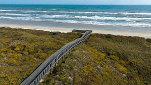 A coastal walkway leading to a beach with a view of the ocean. - Huge Vacation Home! Community Boardwalk to the Beach (Port Aransas)