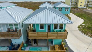 A beachfront property with multiple buildings, a swimming pool, and a wooden deck. - St. Jo's Bungalow (Port Aransas)