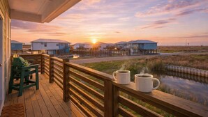 A wooden deck with a view of houses and water. - St. Jo's Bungalow (Port Aransas)