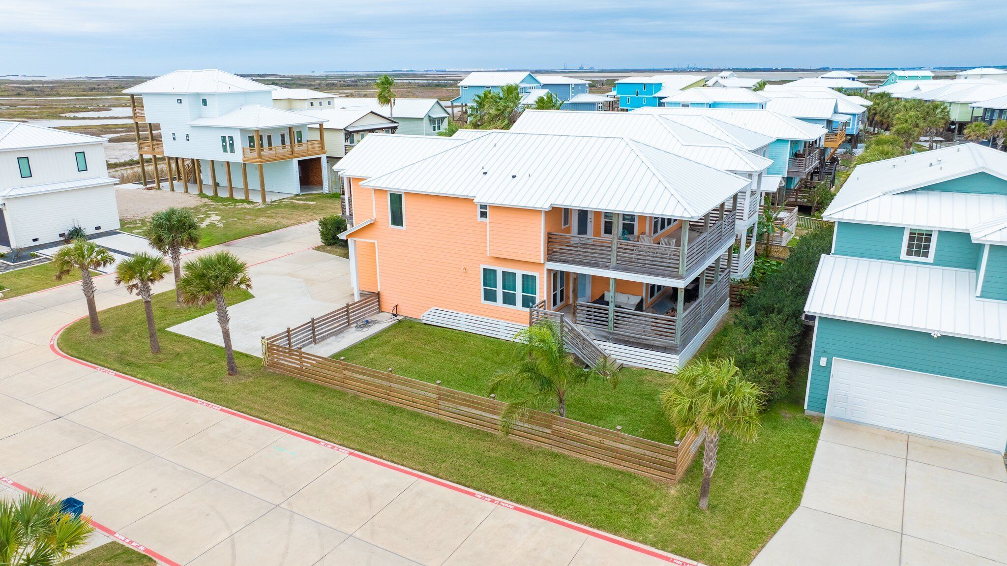 Un quartier résidentiel en bord de mer, avec des maisons modernes, un bâtiment central doté d’un balcon et une vue dégagée sur l’océan.