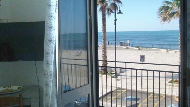 A view from a balcony overlooking a beach with palm trees and a clear sky. - Laura's House - Aspra Sea View (Bagheria)