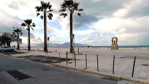 A paved promenade with palm trees, a sculpture, and a view of the sea. - Laura's House - Aspra Sea View (Bagheria)