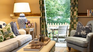 A cozy living room with a sofa, armchair, and a small table with a lamp and decorative items. - Stable Cottage -  a super cottage sleeping 2 guests (Pulborough)