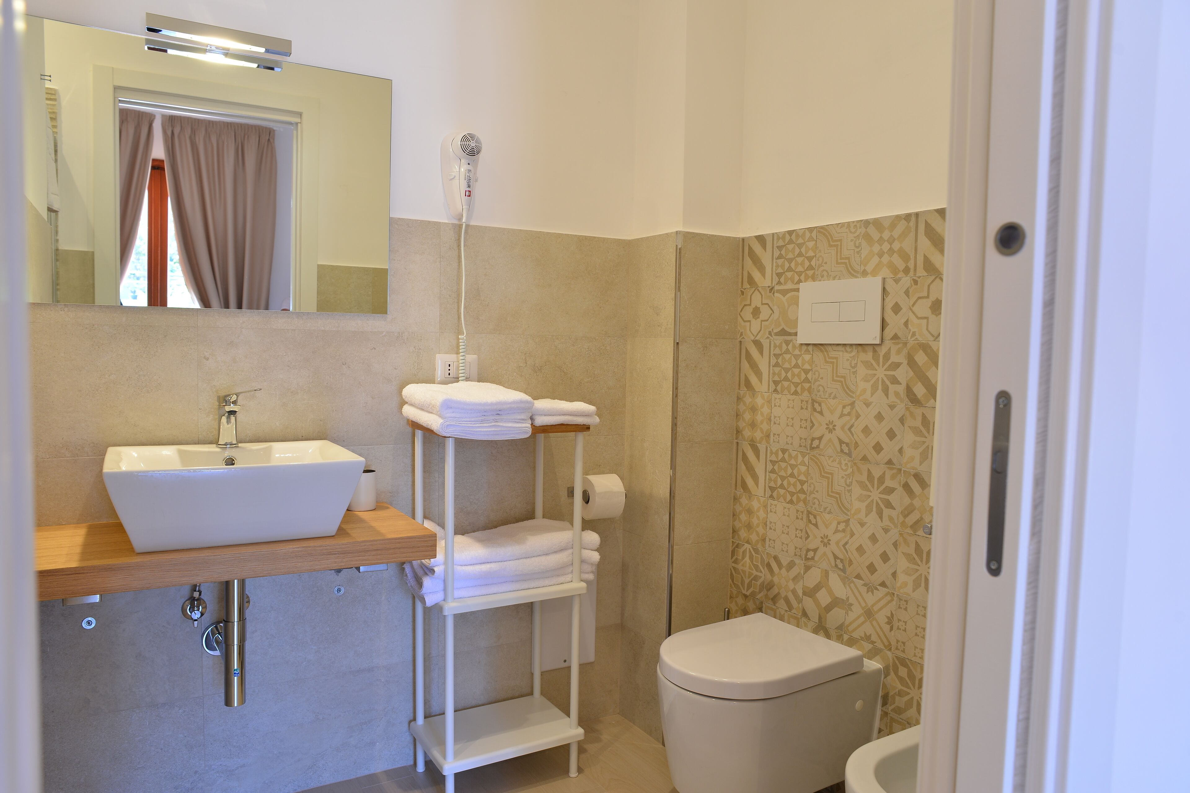A bathroom with a sink, toilet, towel rack, and a shower area.