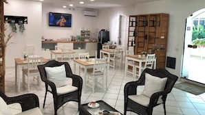 A spacious room with a dining area, kitchen, and a television mounted on the wall. - Villa Miriam (Gragnano)