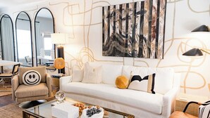 A modern living room with a white sofa, a round coffee table, and a large abstract painting on the wall. - Game day luxury! New! 3 king en suites; 17 min walk to UM; 5 mins to sq; (Oxford)