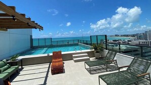 A rooftop pool with a clear view of the ocean, a wooden pergola, and outdoor seating. - Smart Stay Apto 807-Mandi Hospitalidade (Maceio)