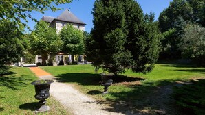Ein gepflegter Garten mit einem Weg, der zu einem Gebäude mit grauem Dach und Steinmauern führt.