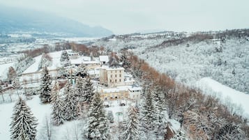Eine verschneite Landschaft mit einem großen Gebäude, umgeben von Bäumen.