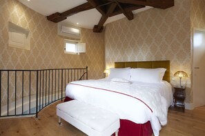 Un dormitorio con una cama grande, techo de madera y papel tapiz estampado.