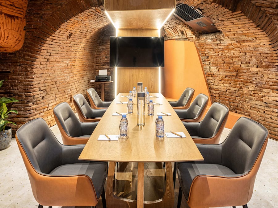 Uma sala de conferências com uma mesa comprida, seis cadeiras e uma tela grande.