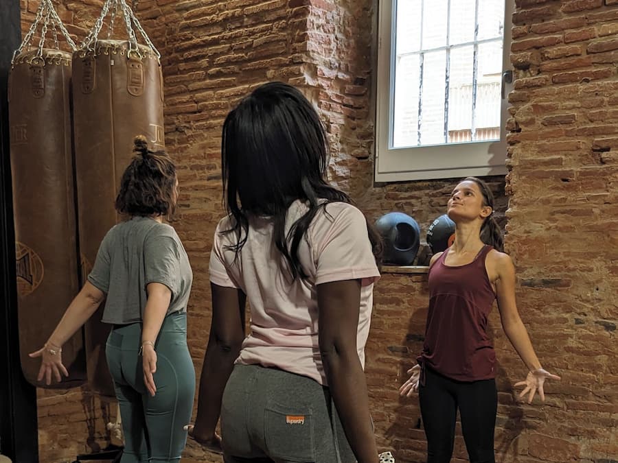 A brick-walled room with wooden flooring, a punching bag, and mats for exercise.
