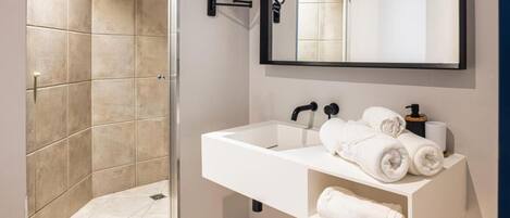 Ein modernes Badezimmer mit Dusche, Waschbecken und Spiegel.