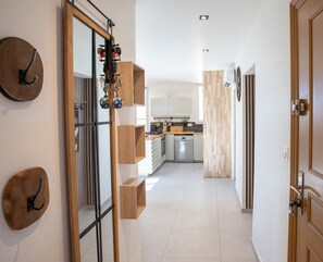 Enter a well-appointed hallway leading to a kitchen with white cabinets, a dishwasher, and wooden countertop.
