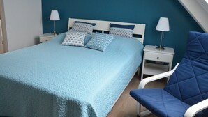 A bedroom with a bed, two bedside tables, a chair, and a lamp. - New waterfront rental with sea view (Plomodiern)