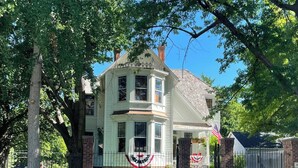 A two-story house with a brick facade, large windows, and a front porch.