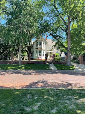 A two-story house with a brick facade, a front porch, and a flag in front.
