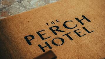 En brun dørmåtte med teksten 'The Perch Hotel'.