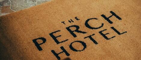 Un paillasson marron sur lequel est inscrit « The Perch Hotel ».