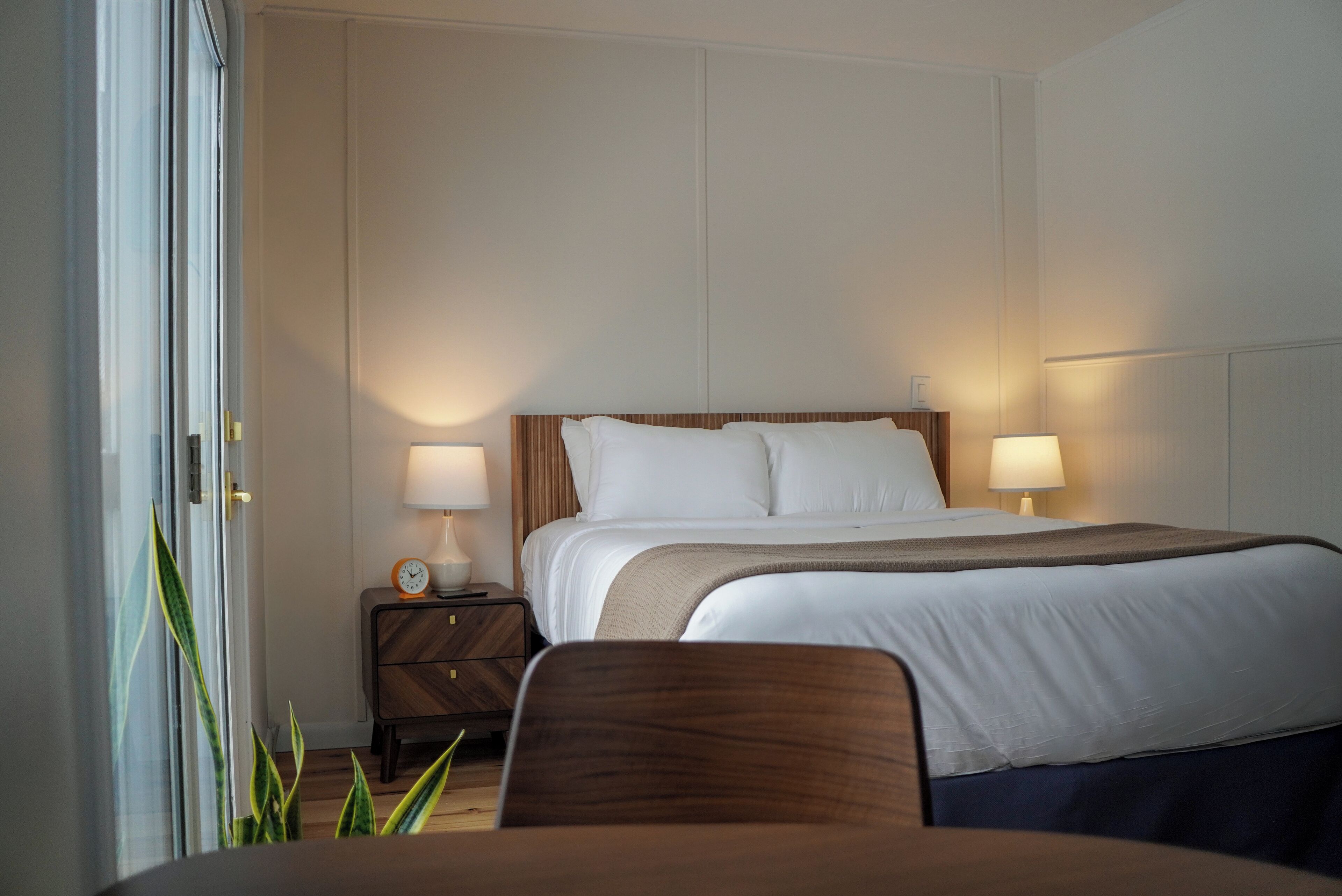 A hotel room with a bed, bedside tables, lamps, and a chair.