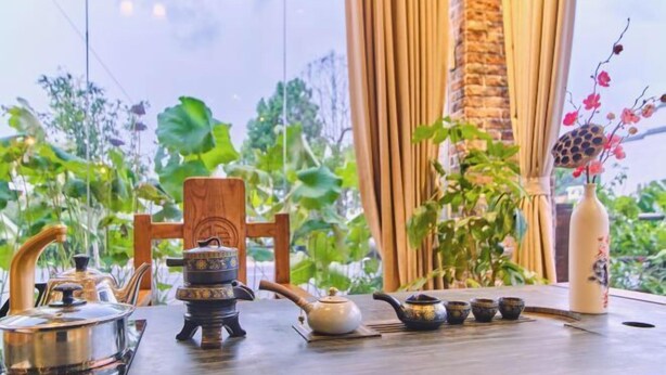 A table set with teapots and cups, a decorative vase, and a wooden chair. - Danxia Mountain Fengqing Hostel (Renhua)