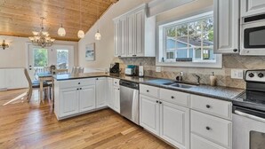 A modern kitchen with white cabinets, a built-in oven, and a large window. - Welcome to Playcation - fun for all ages! (Moneta)