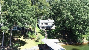 A lakeside cabin with a dock extending into the water, surrounded by dense trees. - Welcome to Playcation - fun for all ages! (Moneta)