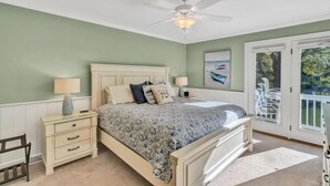 A bedroom with a bed, nightstands, a ceiling fan, a window with a view, and a door leading to an outdoor area. - Welcome to Playcation - fun for all ages! (Moneta)
