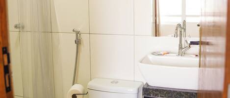 A bathroom with a toilet, shower, and sink.