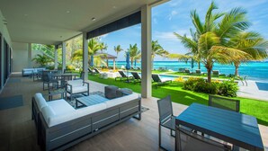 A modern outdoor living area with a pool, lounge chairs, and a view of the ocean. - 3 Bedroom Luxury Oceanfront Condo (Bodden Town)