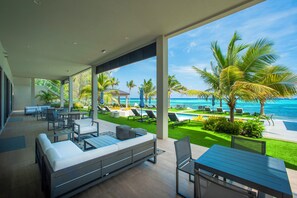 A modern outdoor lounge area with a pool, seating, and a view of the ocean. - 3 Bedroom Luxury Oceanfront Condo (Bodden Town)