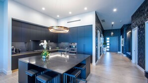 A modern kitchen with a central island, built-in appliances, and a pendant light. - 3 Bedroom Luxury Oceanfront Condo (Bodden Town)