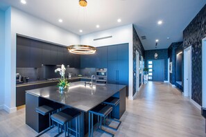 A modern kitchen with a central island, built-in appliances, and a pendant light. - 3 Bedroom Luxury Oceanfront Condo (Bodden Town)