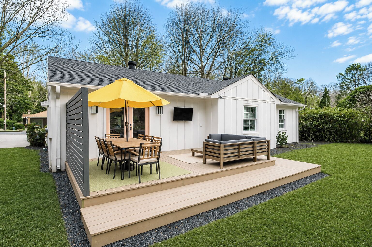 A house with a patio, a dining table with chairs, and a sofa.