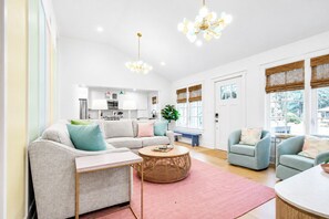 Ein modernes Wohnzimmer mit einer Couch, Sesseln, einem Couchtisch und einem Essbereich.