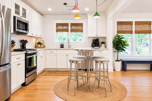 Une cuisine moderne avec des meubles blancs, des appareils en acier inoxydable et un îlot central doté de tabourets de bar.