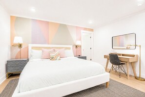 Une chambre à coucher moderne avec un lit, des tables de chevet, un bureau et un miroir.