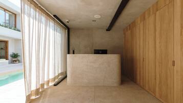Un interior moderno con una recepción, un armario de madera y un ventanal con cortinas.