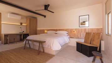 Un dormitorio moderno con una cama grande, un escritorio, una silla y un taburete pequeño.