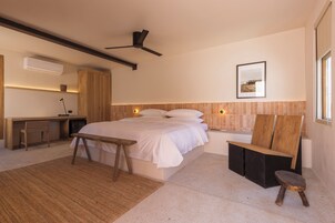 Un dormitorio moderno con una cama grande, un escritorio, una silla y un taburete pequeño.
